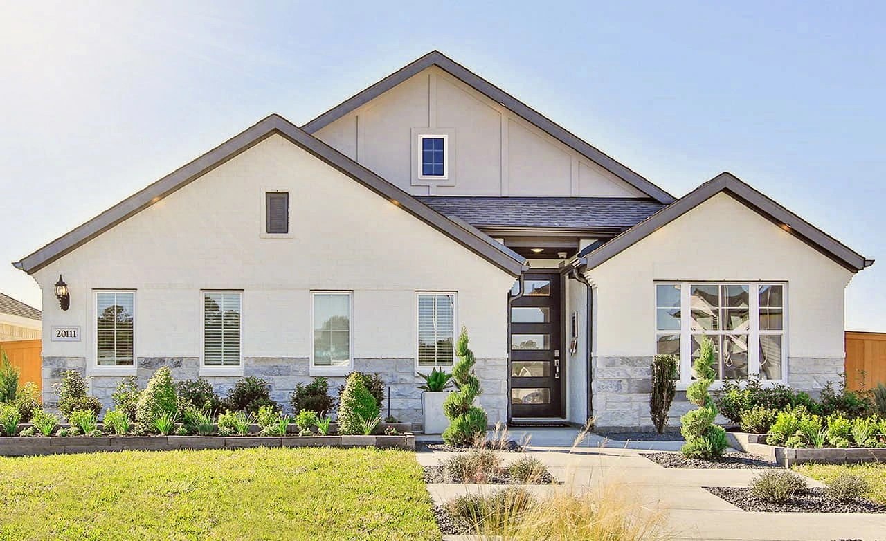 Modern white house with stone accents, large windows, manicured garden in Cypress Green community.