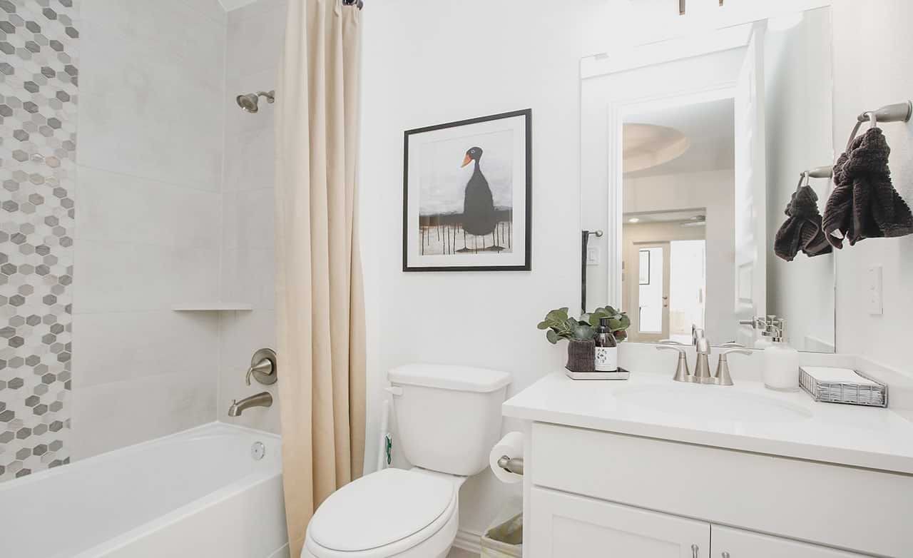 Modern bathroom with hexagonal tile shower, elegant fixtures, and framed art in Cypress Green community.