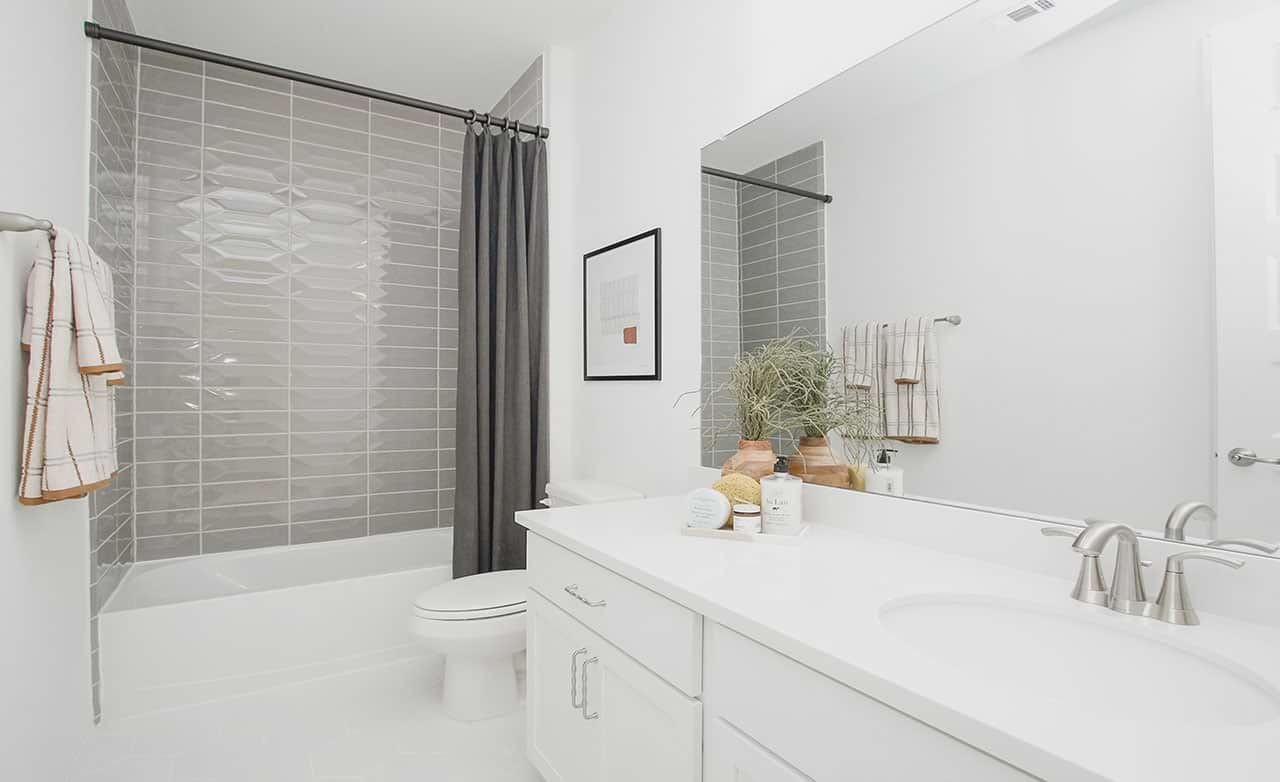 Modern bathroom with white vanity, gray tile backsplash, and elegant fixtures in Cypress Green.