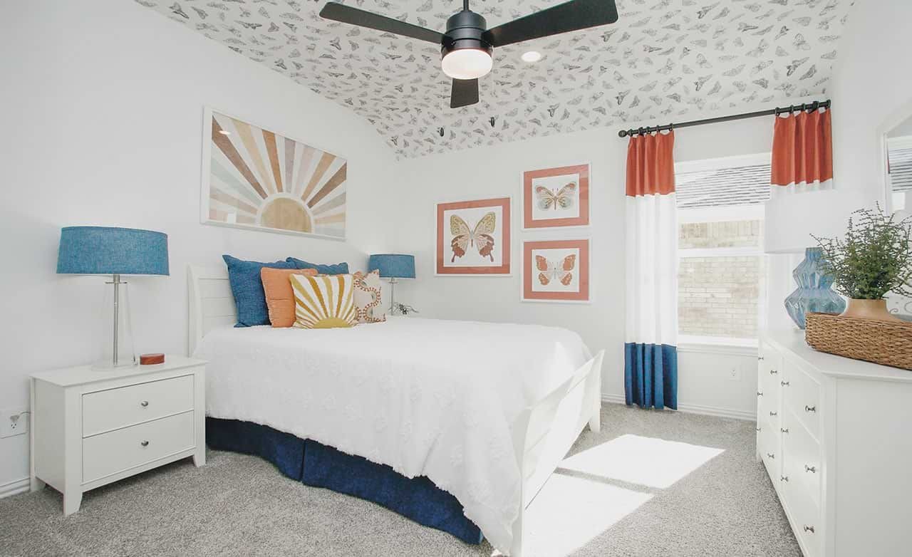 Stylish bedroom with butterfly-themed ceiling, sunburst art, vibrant curtains, and plush bedding in Cypress Green.