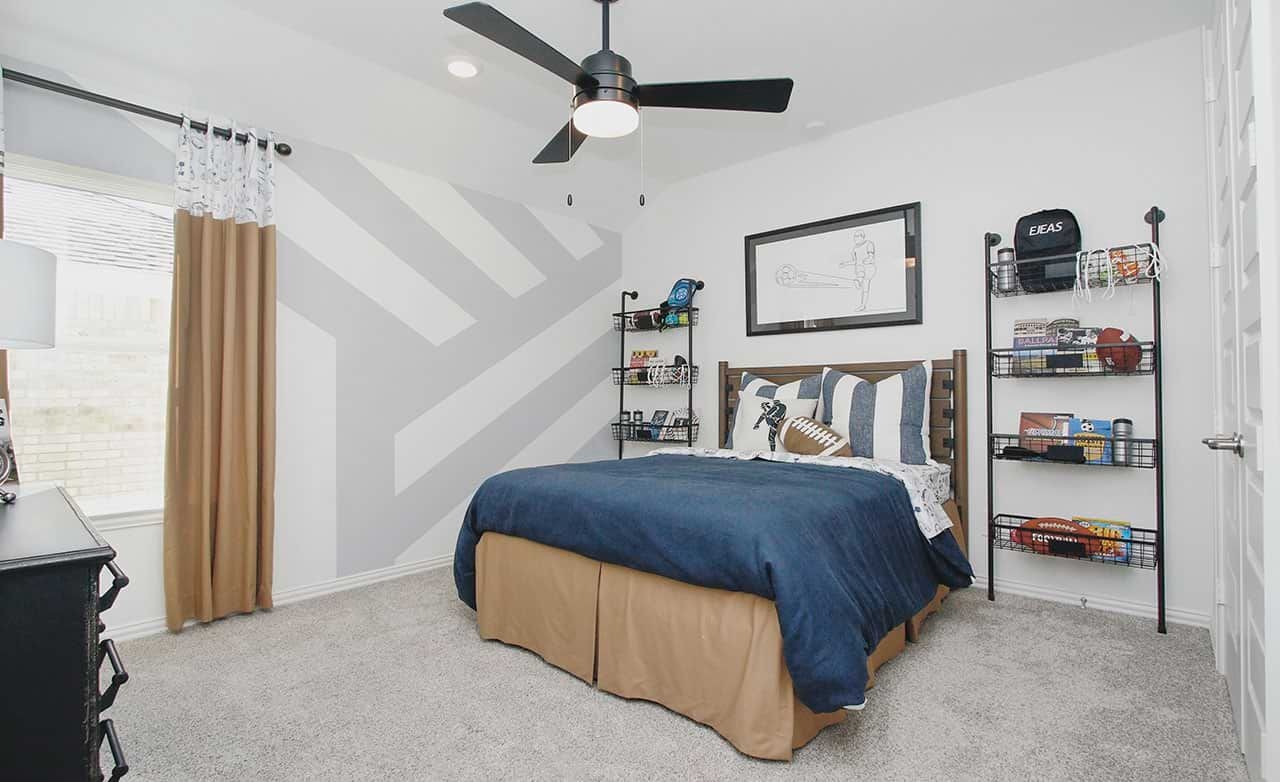 Modern bedroom in Cypress Green with geometric accent wall, ceiling fan, and sporty decor. Cozy and stylish design.