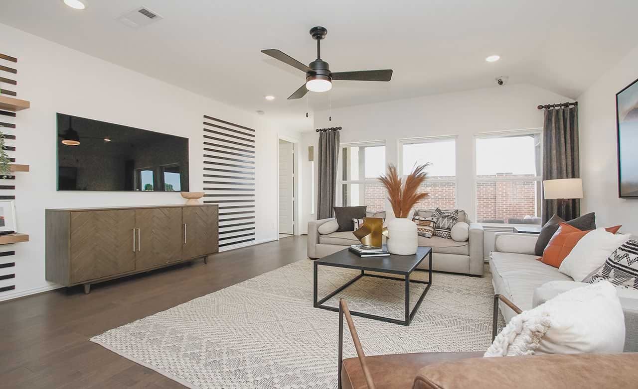 Modern living room with a striped accent wall, large TV, and elegant decor in Cypress Green community.
