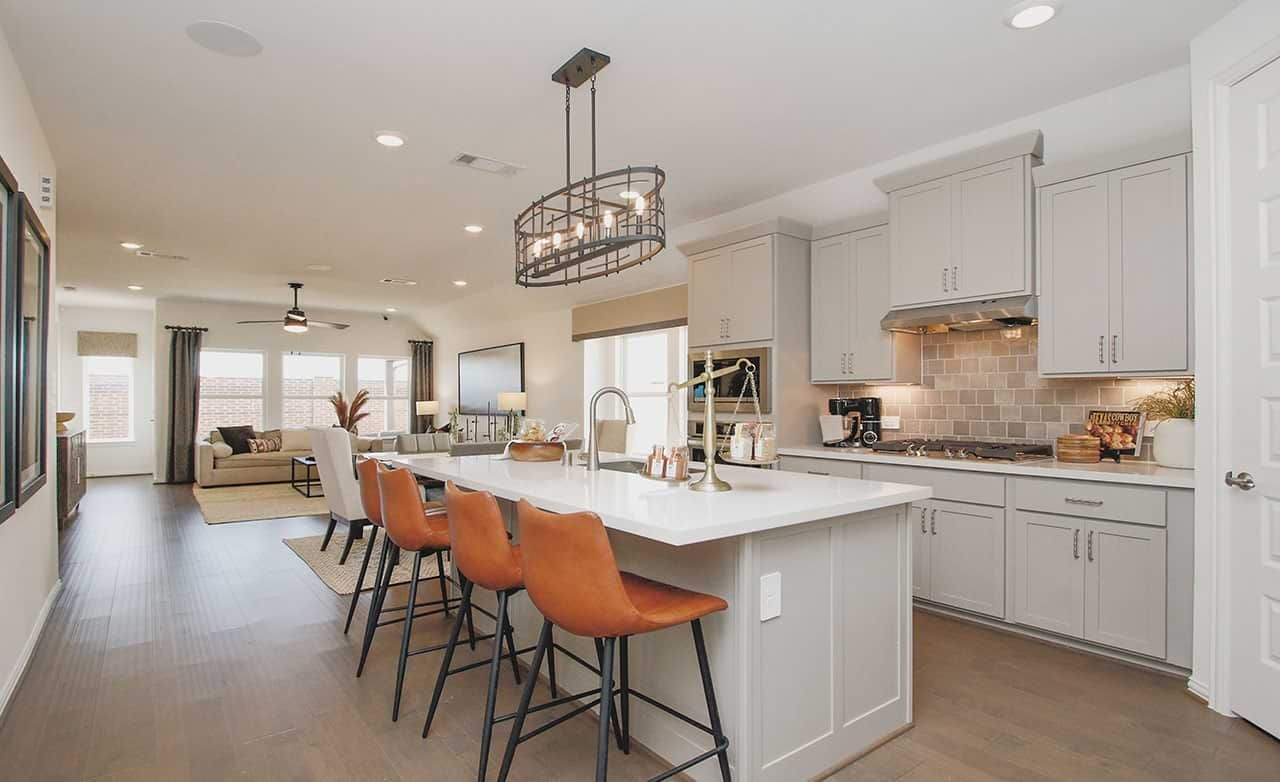 Modern open-concept kitchen in Cypress Green with island, pendant light, hardwood floors.