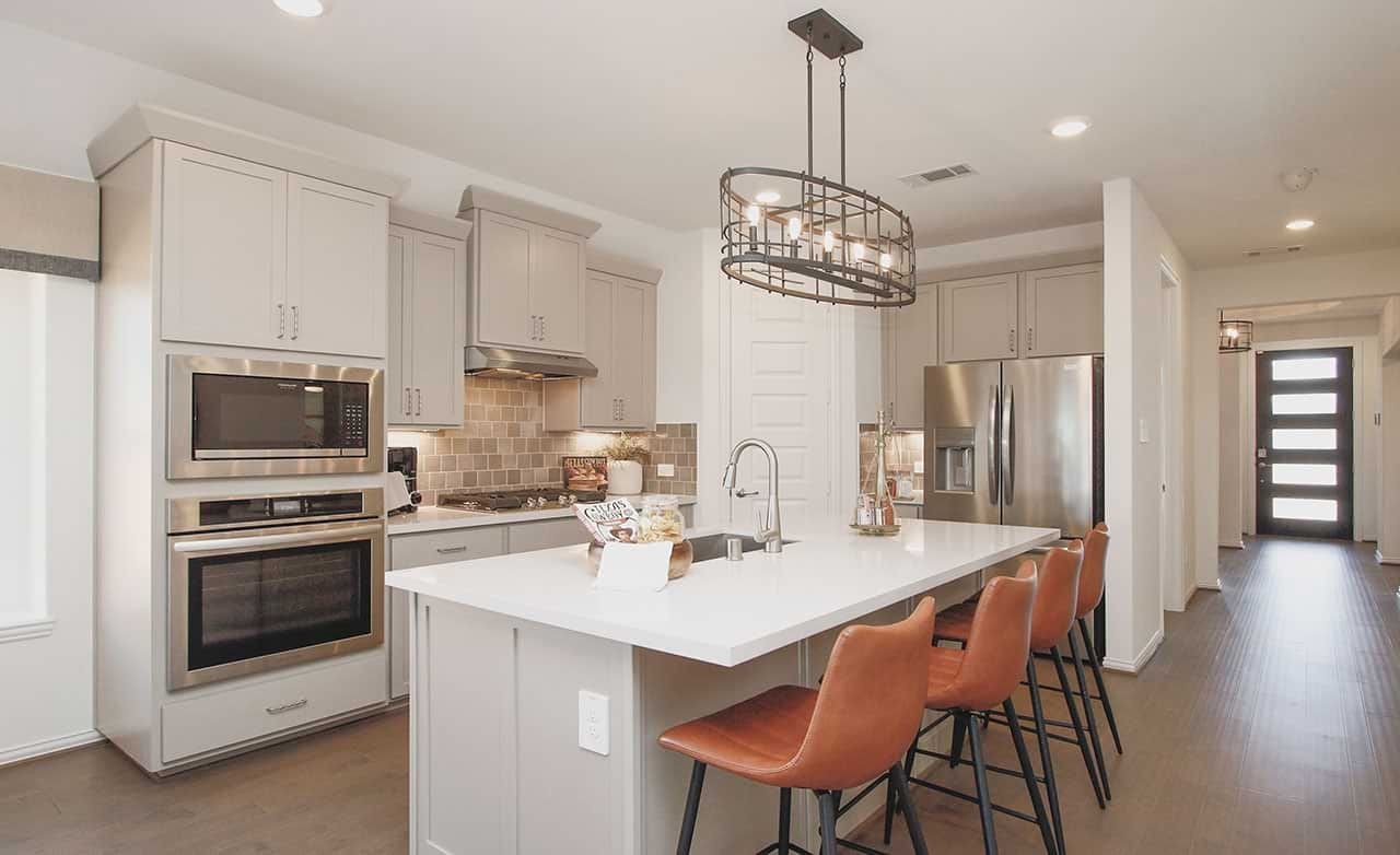 Modern kitchen with quartz island, stainless steel appliances, pendant lighting, in Cypress Green.
