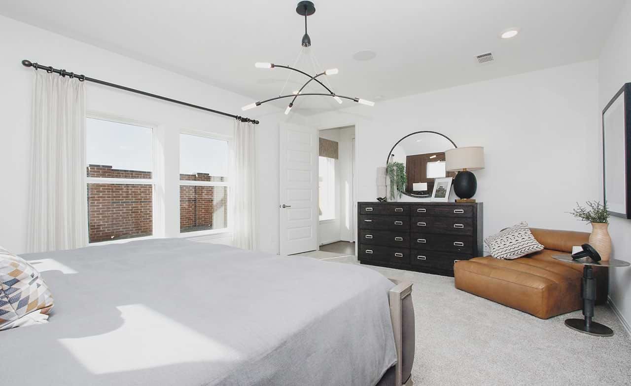 Modern bedroom with sleek lighting, large windows, and chic decor in Cypress Green community.