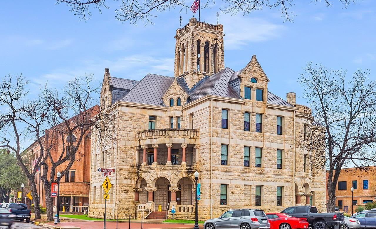 Historic stone courthouse with arched windows and tower, located in Comal County, Texas.