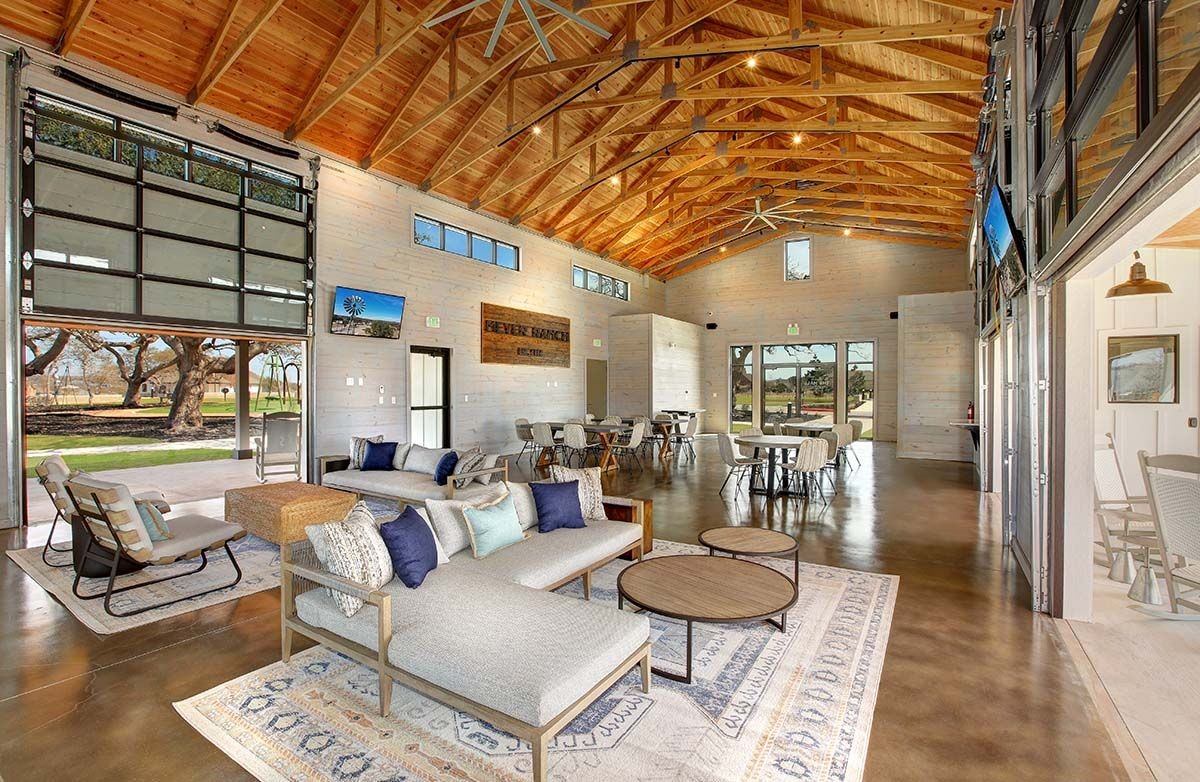 Modern communal area with exposed wooden beams, large windows, and stylish seating at Meyer Ranch, Texas.