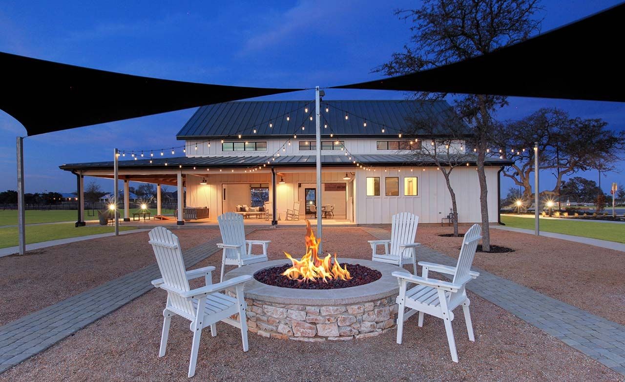Elegant fire pit with Adirondack chairs, barn-style home, string lights, Meyer Ranch.