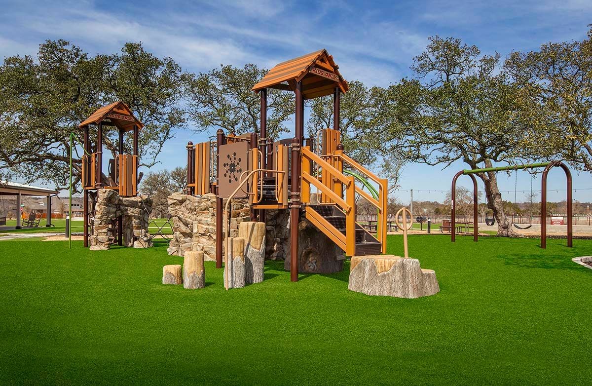 Children's playground with stone structures, wood features, and swings in Meyer Ranch community park.