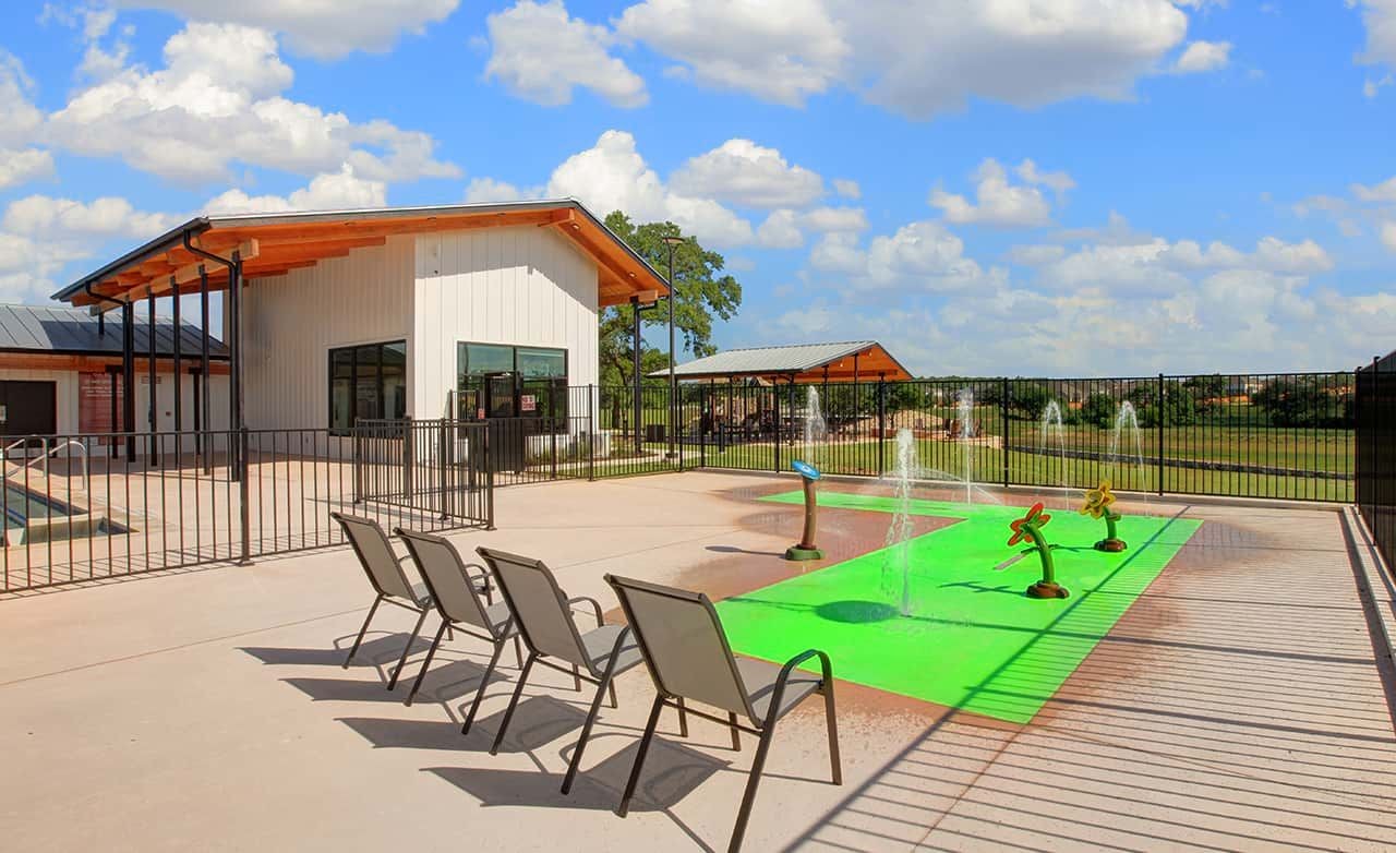 Modern community center with pool and splash pad in Meyer Ranch, featuring sleek architecture and open views.