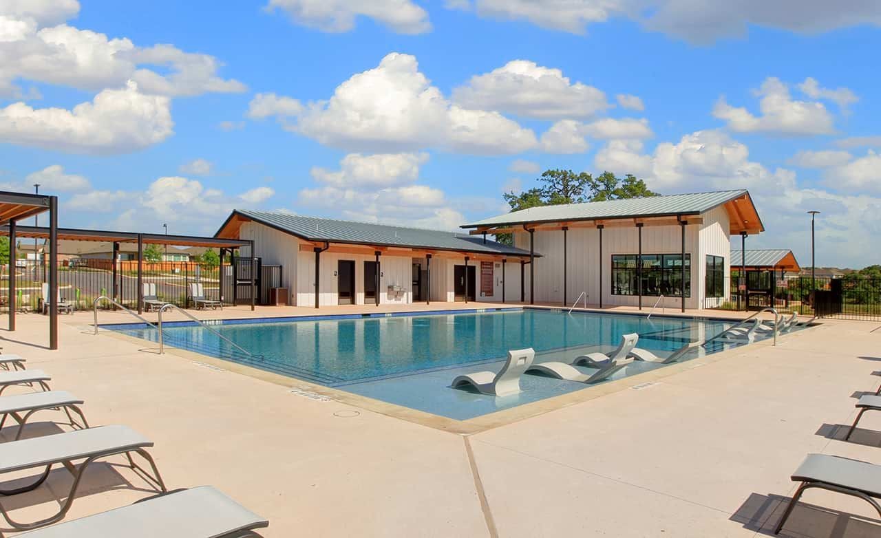 Modern poolside leisure area with chic loungers, sleek buildings, and trees in Meyer Ranch, scenic backdrop.