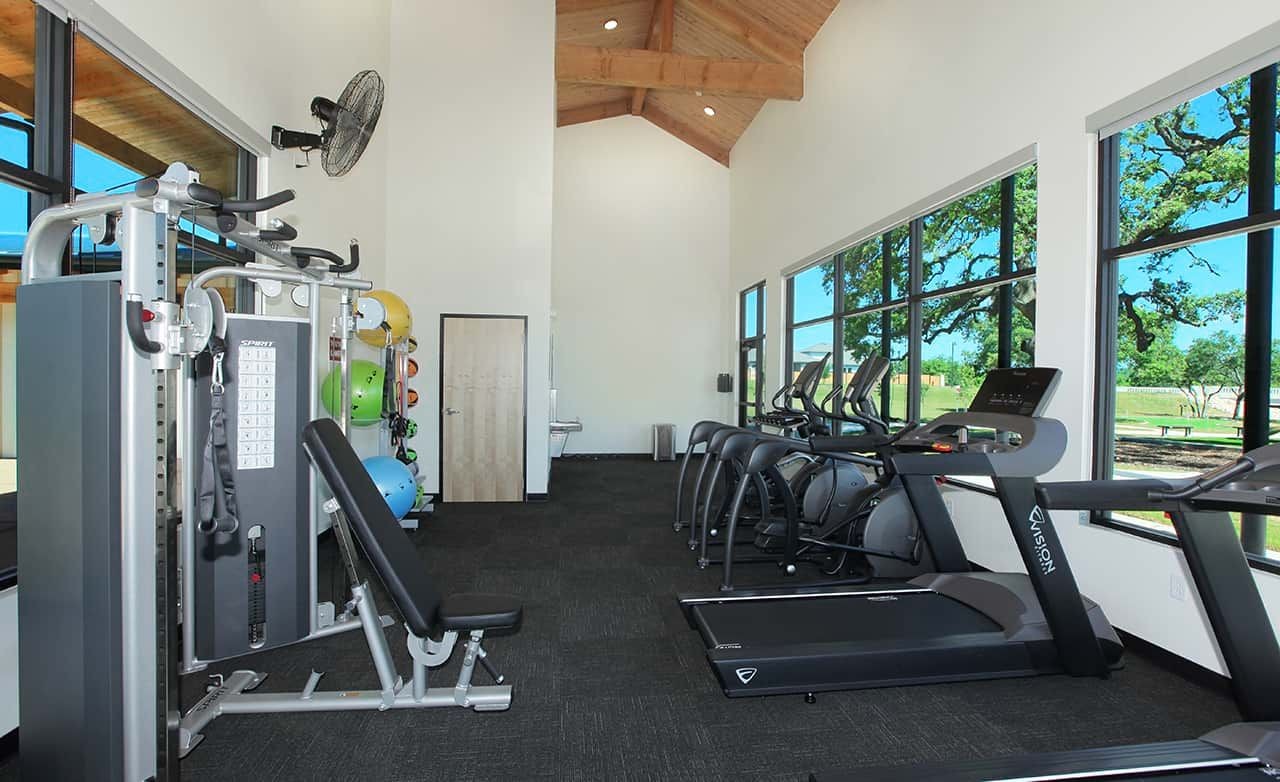 Modern gym with high ceilings, treadmills, weight machines; large windows with scenic view. Meyer Ranch community. 123 characters