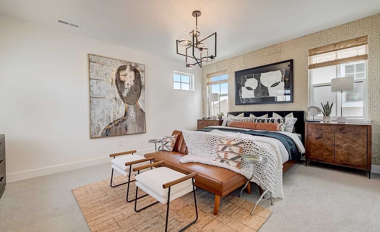 Luxurious bedroom with modern art, plush bedding, leather bench, chic lighting in Westerly community.
