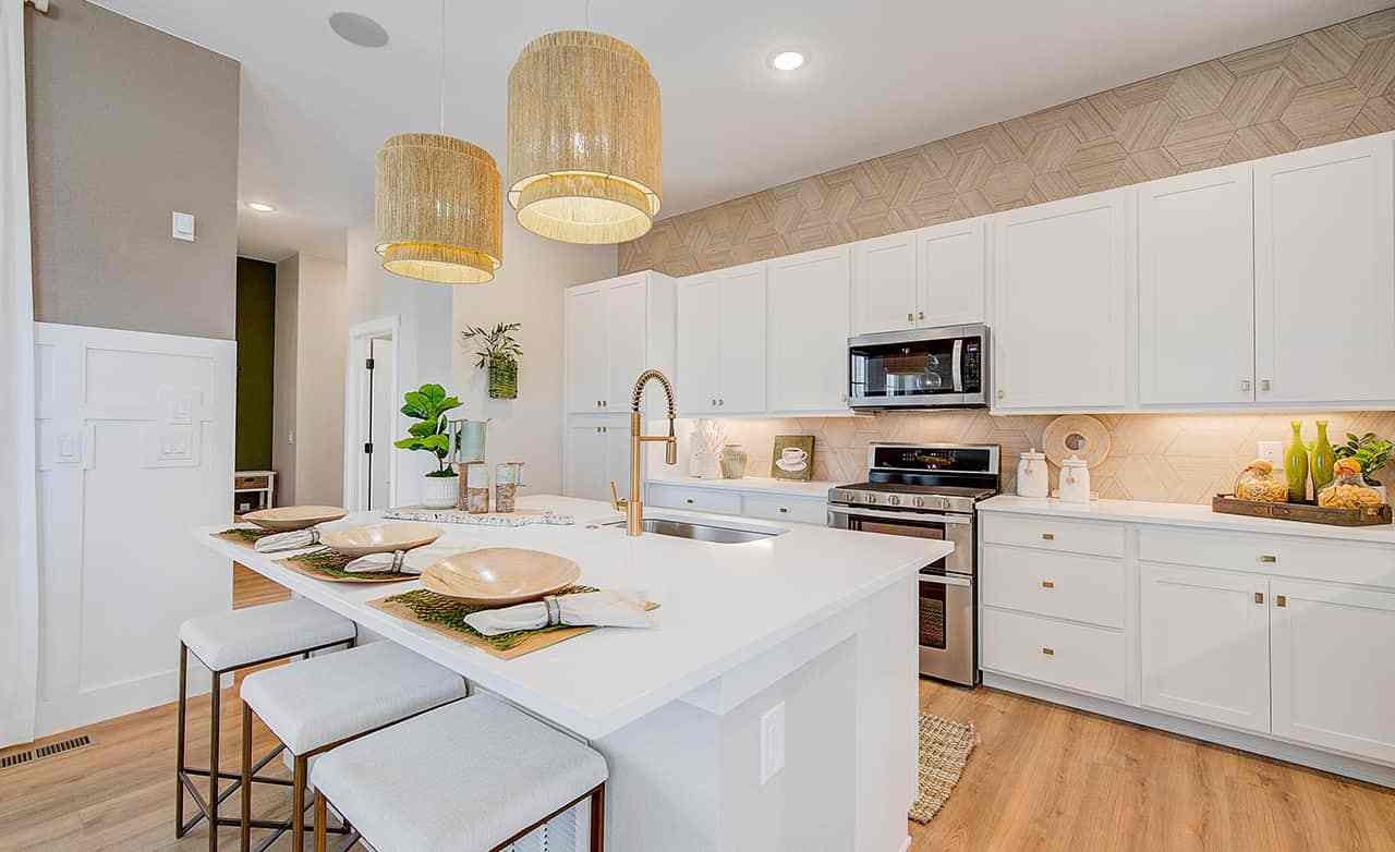 Modern kitchen in luxurious Westerly home with white cabinets, large island, and chic pendant lights.