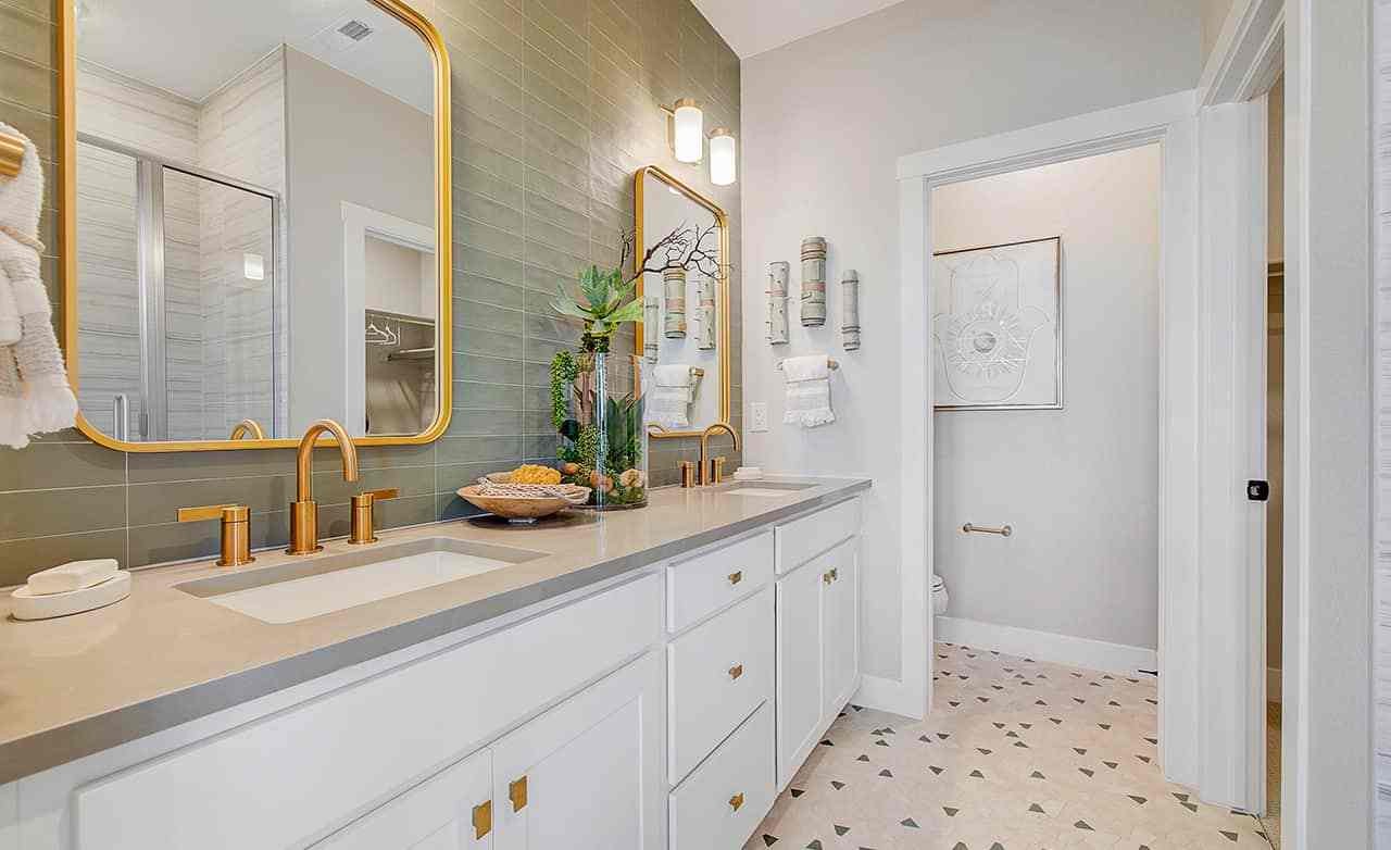 Elegant bathroom with dual vanity, gold fixtures, green tile backsplash, Westerly community.