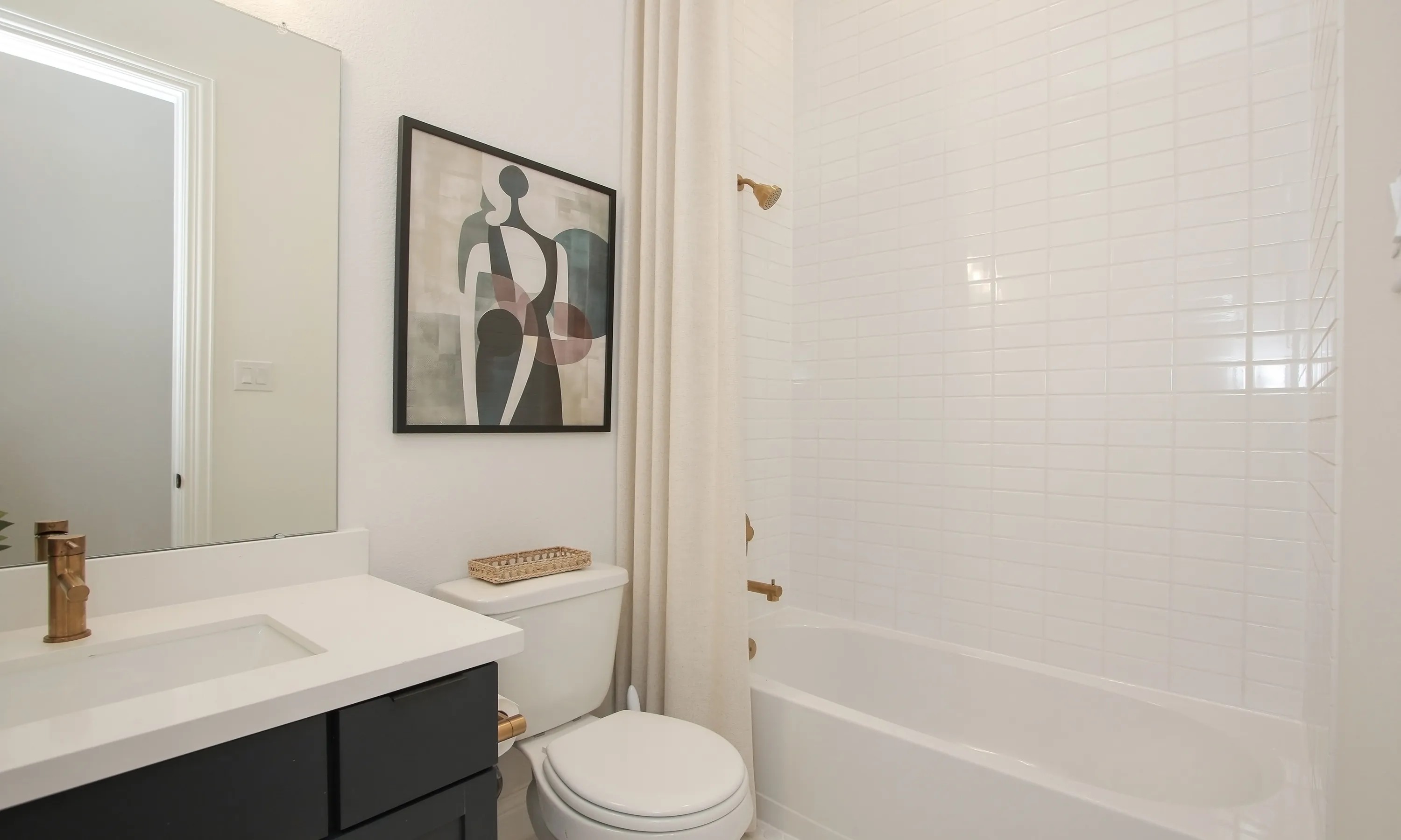 Coastal Point Modern Bathroom with Abstract Art and Brass Fixtures Modern bathroom with white tiles, abstract art, brass fixtures in Coastal Point community.