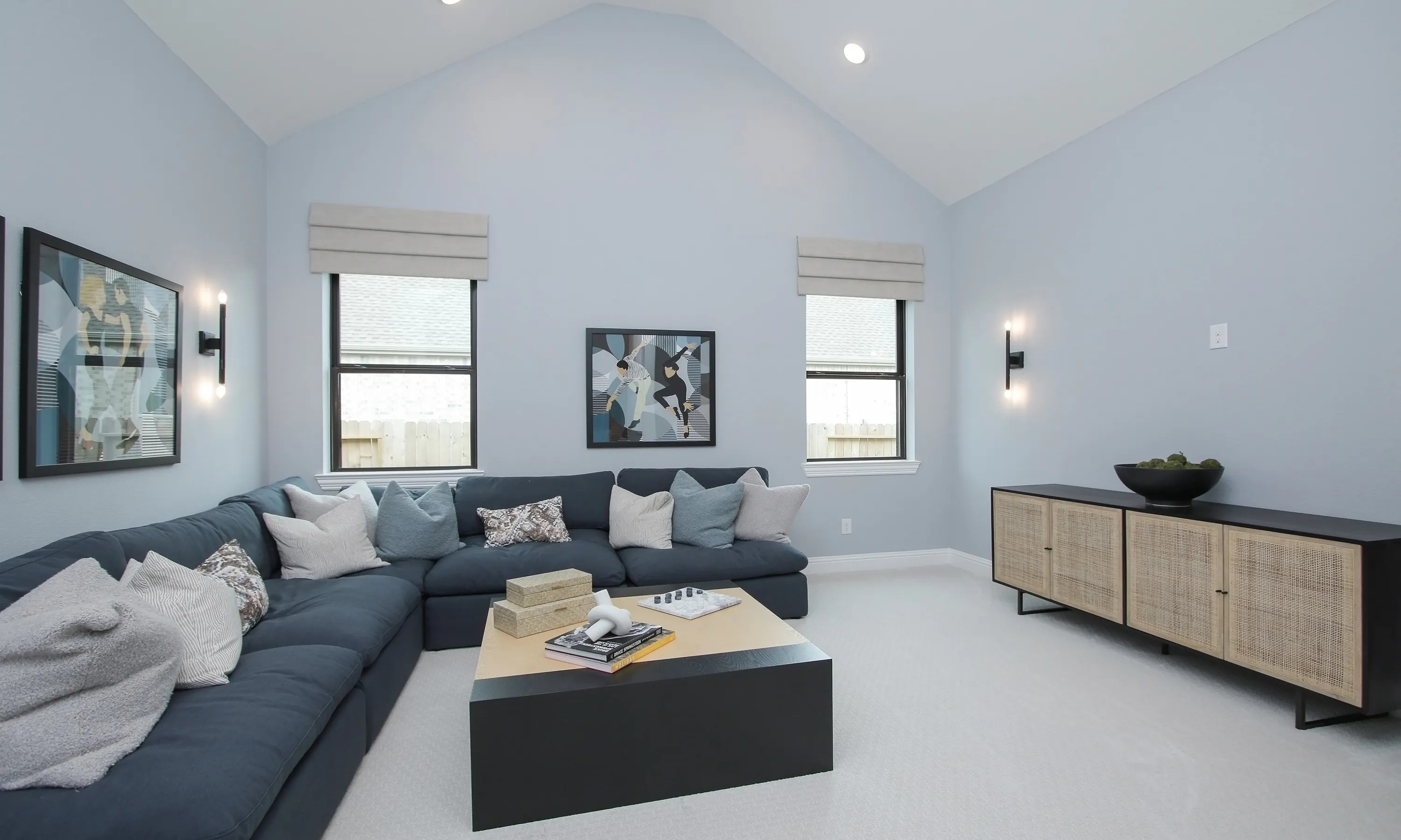 Luxurious Living Room at Coastal Point with Modern Design Elegant Coastal Point room with vaulted ceiling, modern art, cozy blue sectional, large windows.