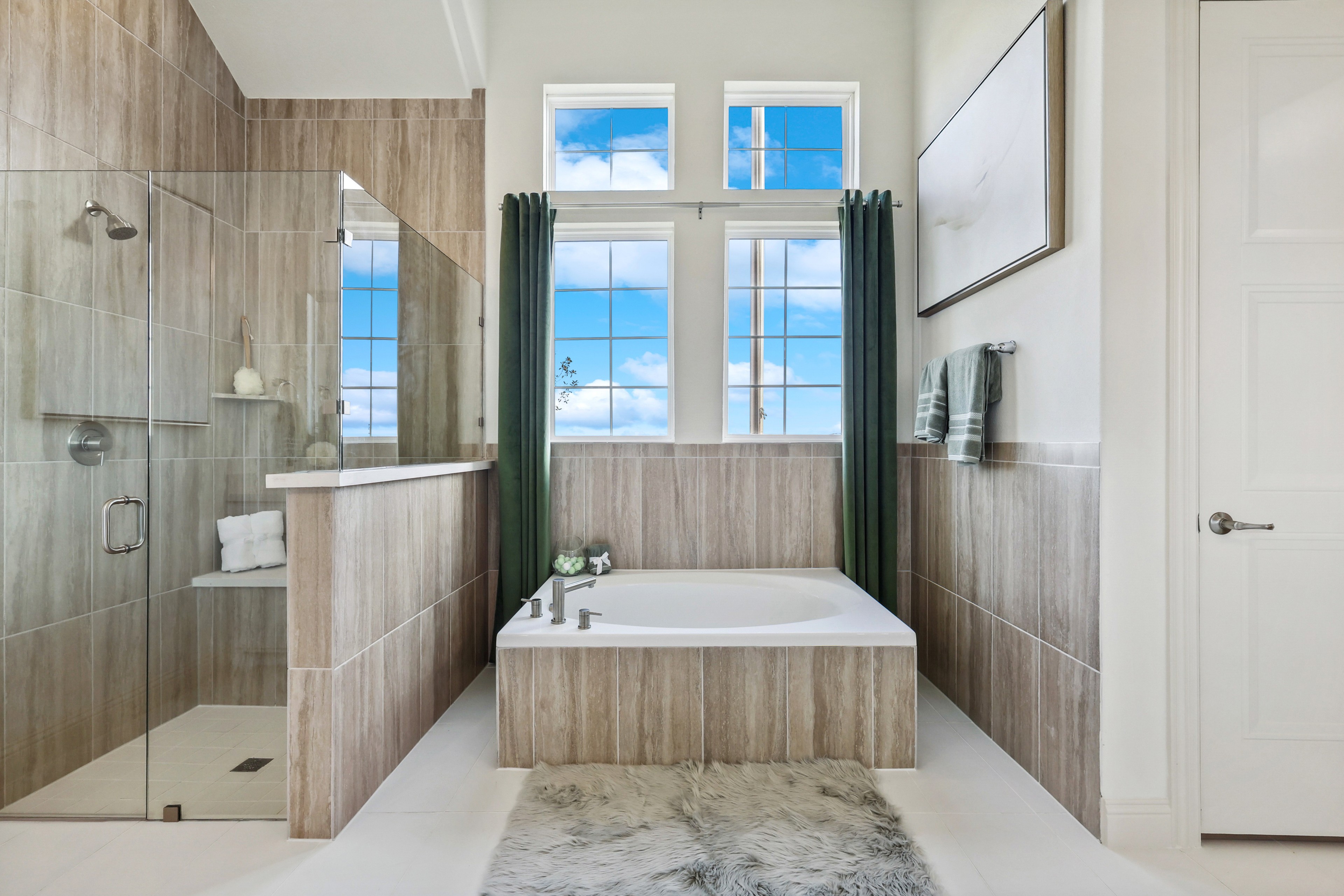 Elegant Bathroom Design with Glass Shower and Tub in Solterra, Texas Luxurious bathroom in Solterra, Texas with glass shower, jetted tub, tiled walls, and large windows with sky view.