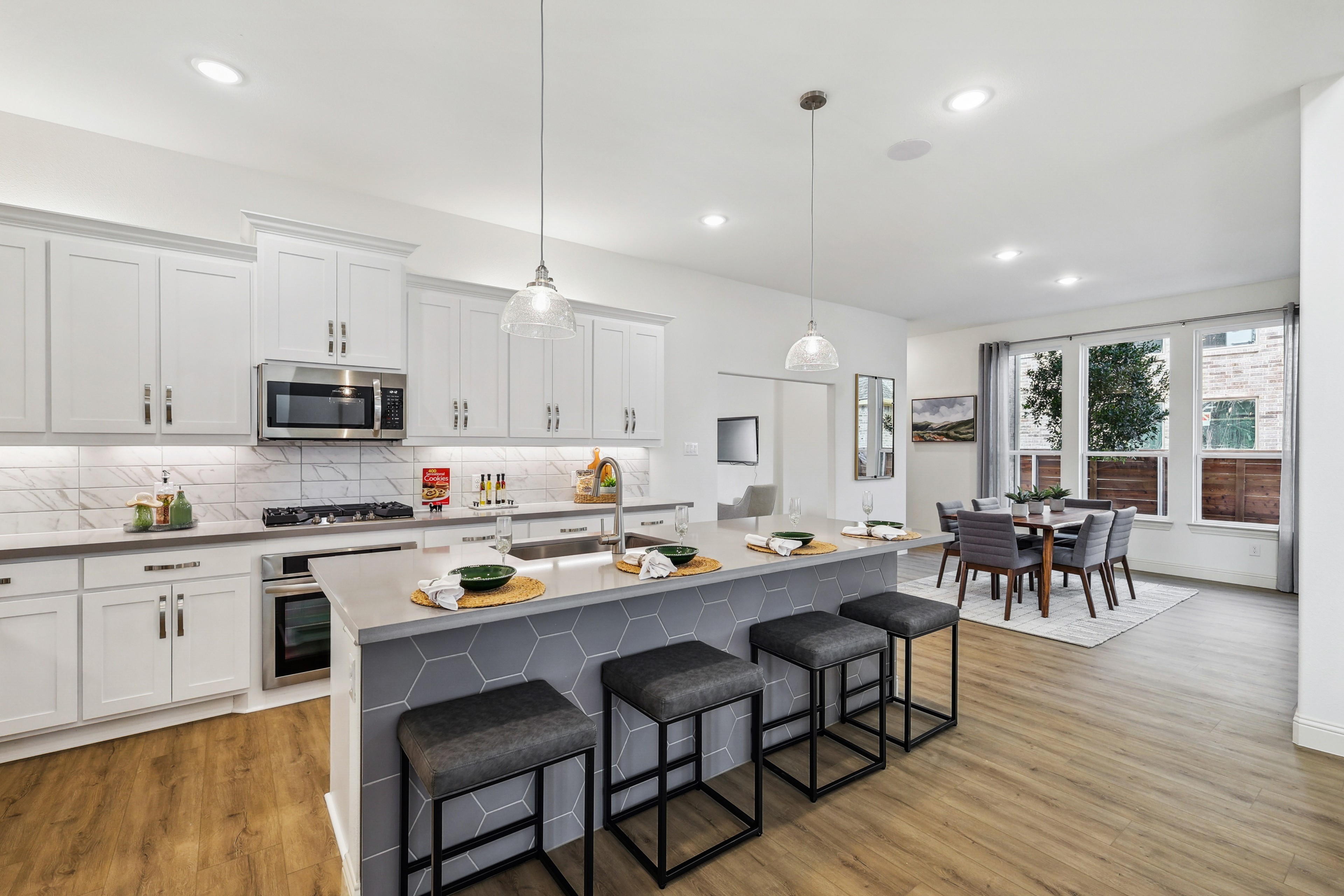 Modern Kitchen and Dining Area in Solterra Texas Home Modern kitchen with hexagon tile island, white cabinets, pendant lights, and open dining area in Solterra Texas home.