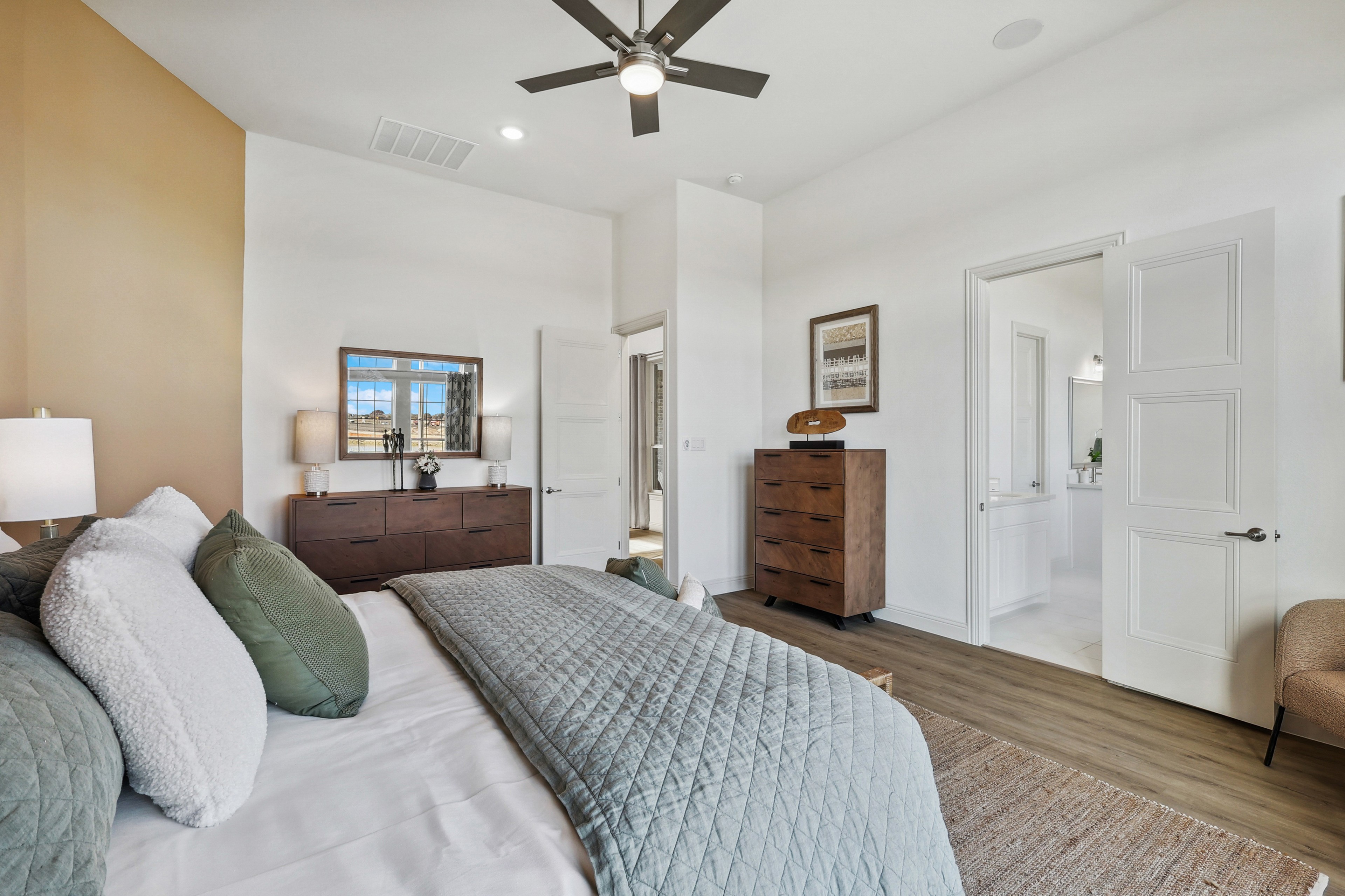 Modern Bedroom Interior in Solterra, Texas with Wood Flooring Modern bedroom in Solterra, Texas, featuring wood flooring, neutral tones, large window, and ceiling fan.