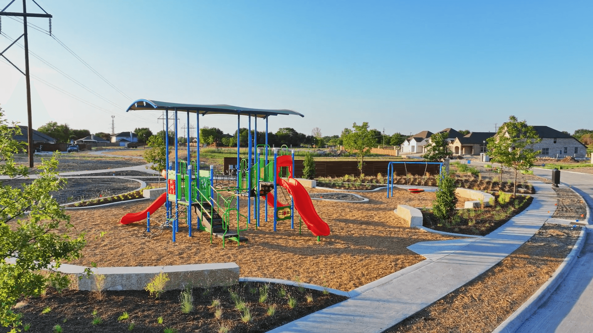 Solterra Texas Playground Area with Vibrant Equipment and Pathways Playground with slides and swings, surrounded by pathways and young trees in Solterra, Texas community park.