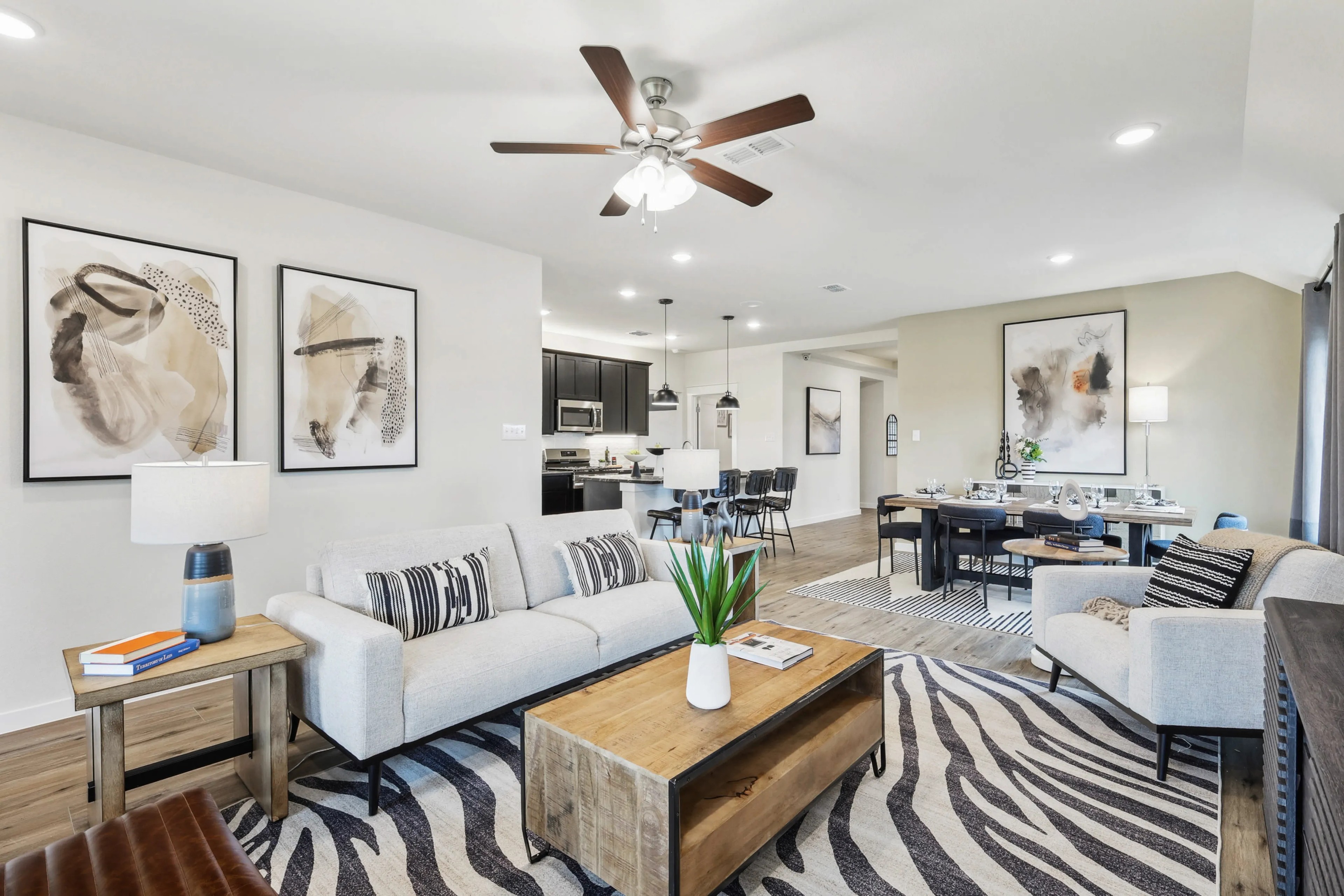 Simpson Crossing Open-Concept Living Room with Modern Decor Modern open-concept living room with elegant decor, Simpson Crossing. Features abstract art, wood floors, ceiling fan.