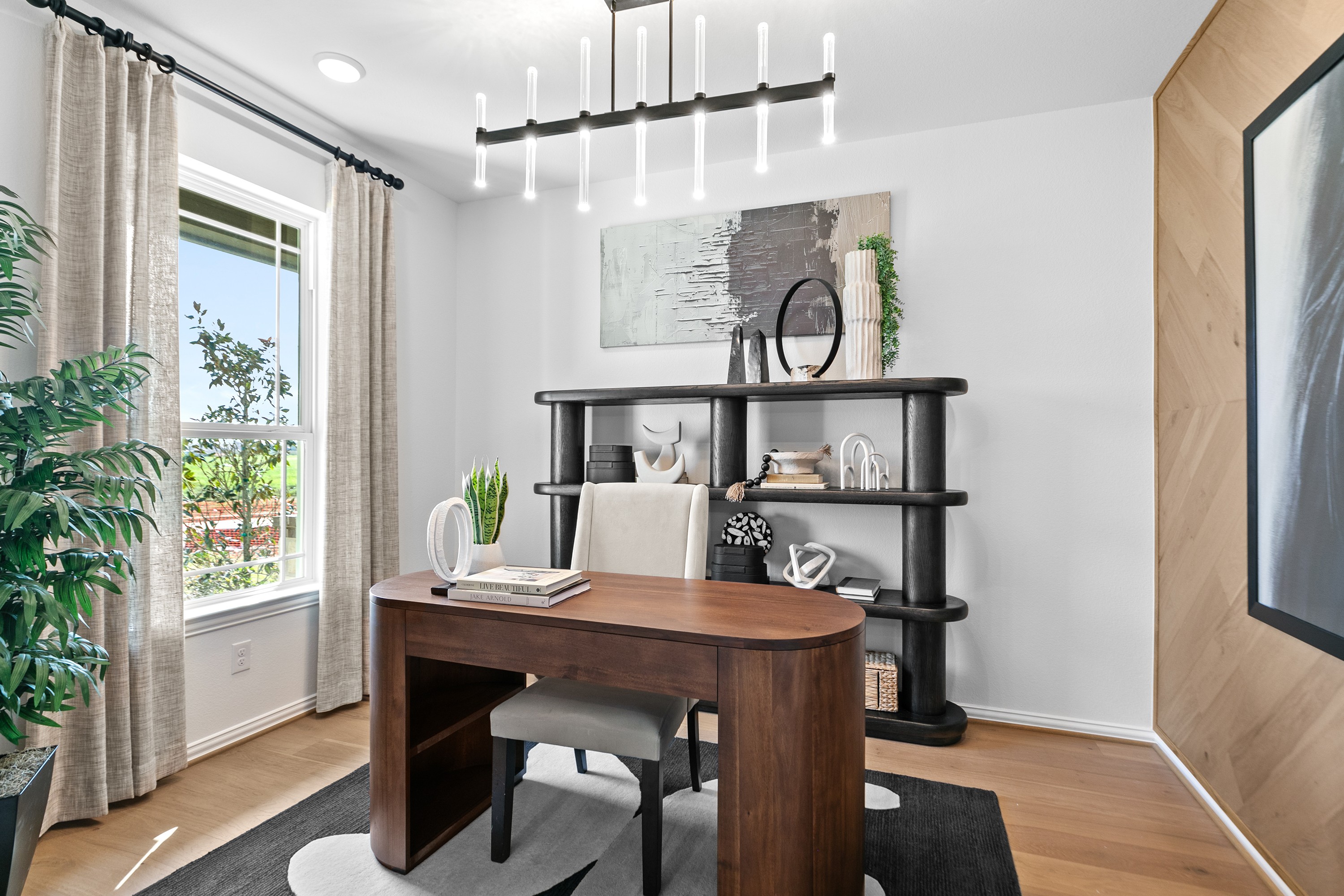 River Ranch Home Office with Modern Chandelier and Wooden Desk Modern home office with wood desk, unique chandelier, and open shelving in River Ranch community. Large window with curtains.