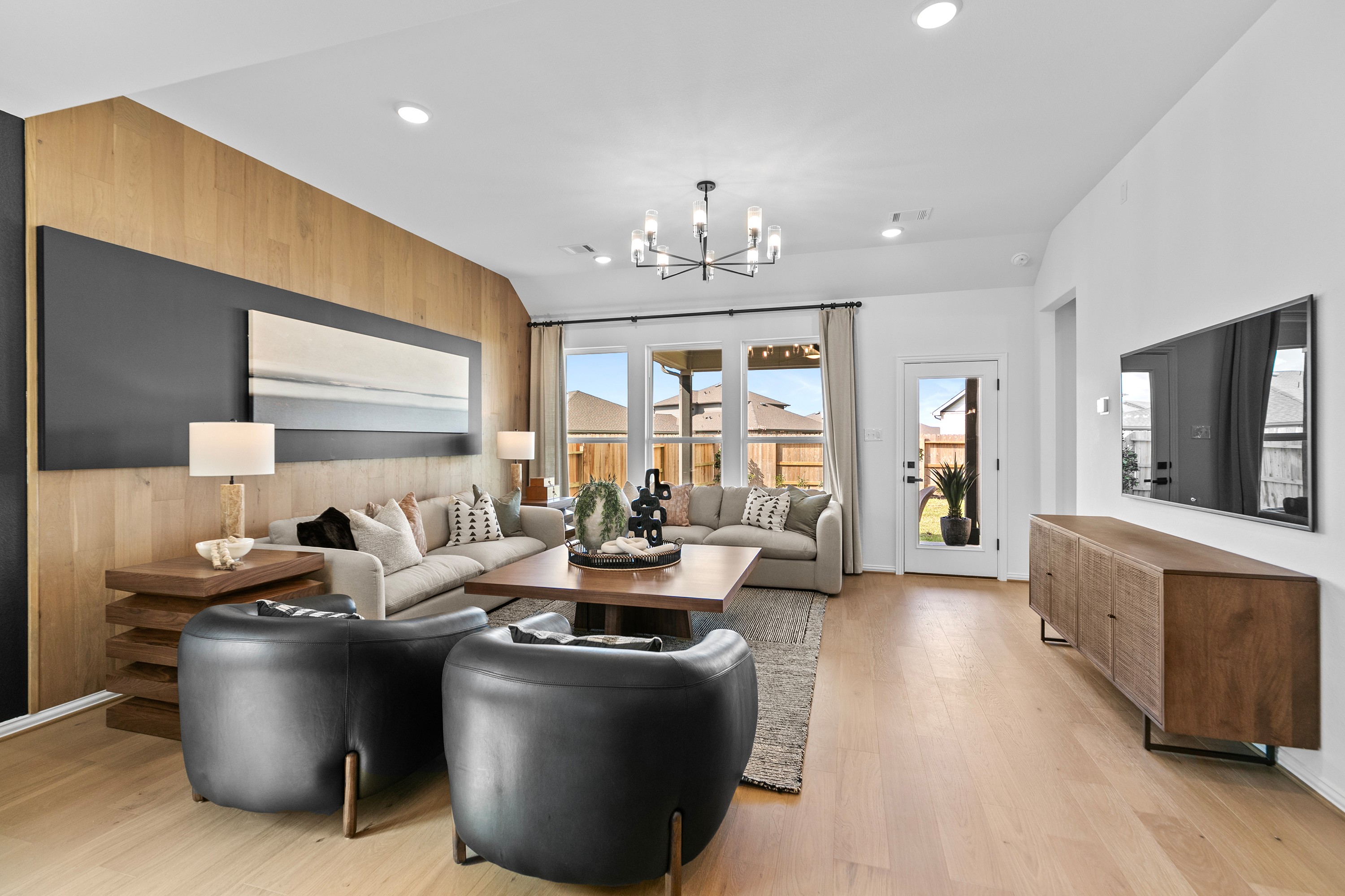 Contemporary Living Room in River Ranch with Patio View Modern living room with wood accent wall, chandelier, and patio view. River Ranch location.
