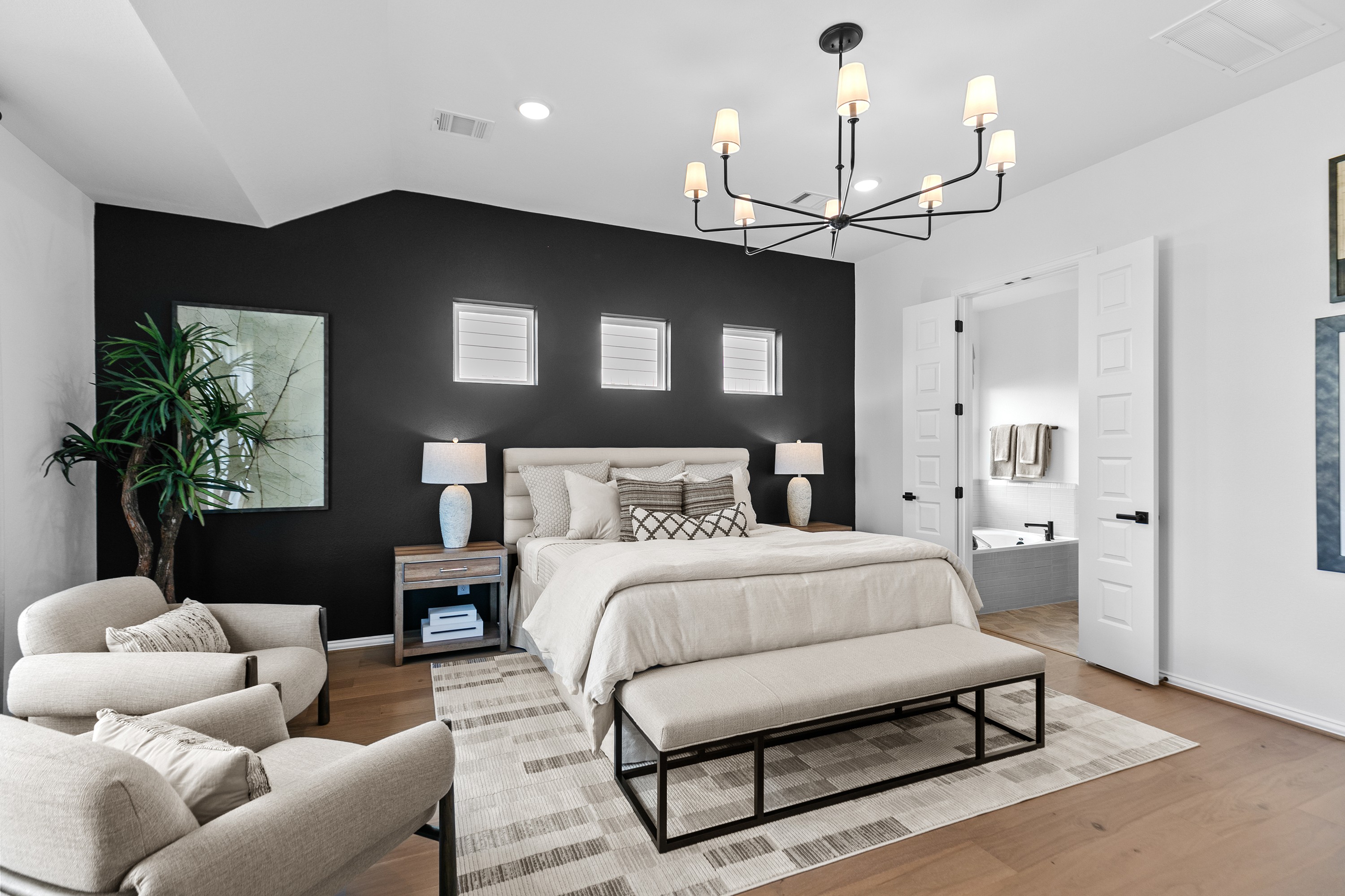 River Ranch Bedroom with Black Accent Wall and Modern Chandelier Elegant River Ranch bedroom with black accent wall, modern chandelier, and en suite door.