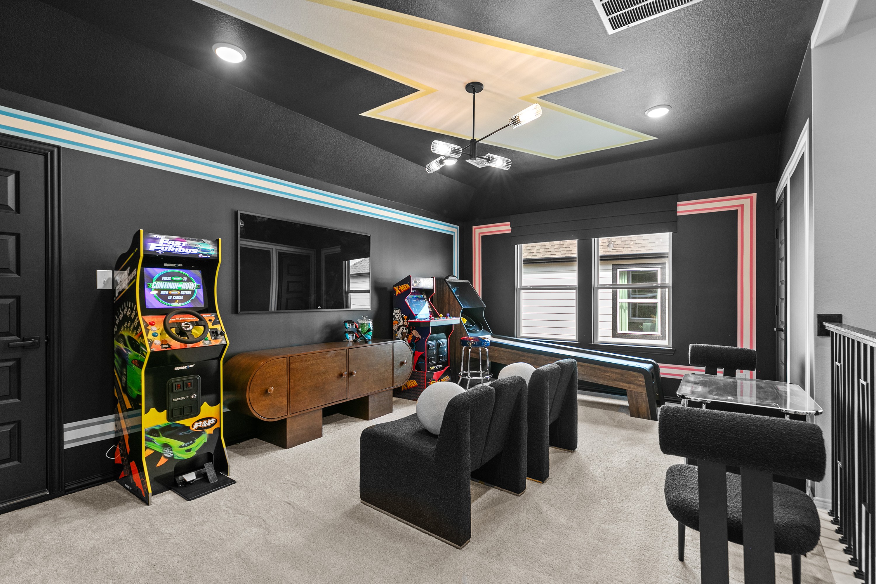 River Ranch Game Room with Arcade Machines and Modern Decor Game room in River Ranch with arcade machines, plush seating, modern decor, and geometric ceiling design.
