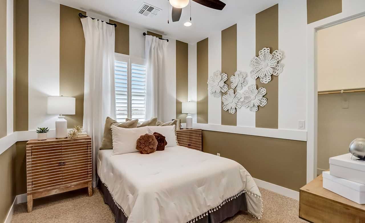 Stylish Canyon Views Hacienda Bedroom with Striped Walls Elegant bedroom with striped walls, white bedding, ornate wall art, located in Canyon Views, Hacienda community.