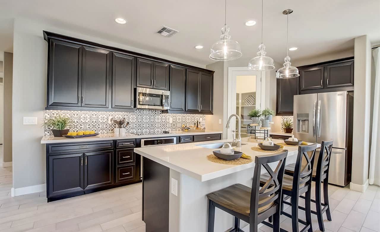 Luxurious Kitchen in Castillo at Anderson Parc, Arizona Modern kitchen with black cabinets, patterned backsplash, and island in Castillo at Anderson Parc, Arizona.