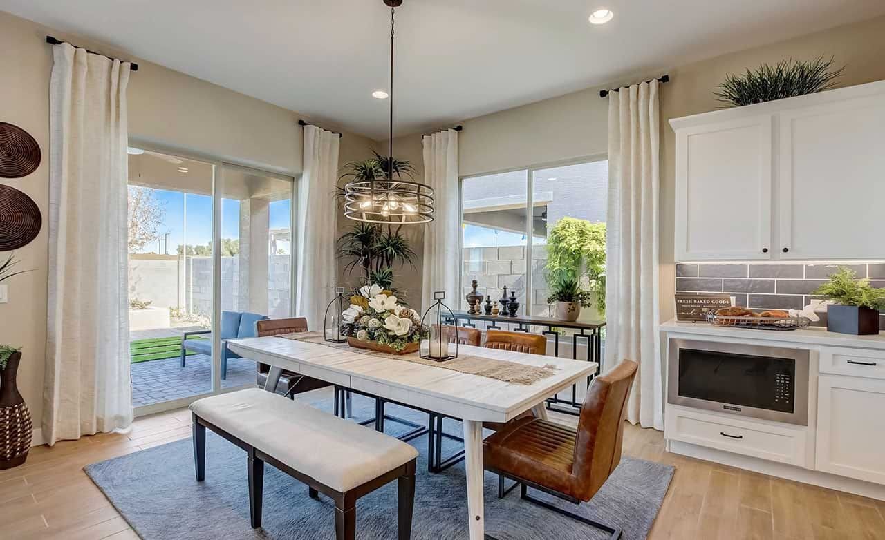 Modern Dining Room in Mirada Crossing with Elegant Decor Elegant dining room with large windows, chic light fixture, and modern decor in Mirada Crossing community.