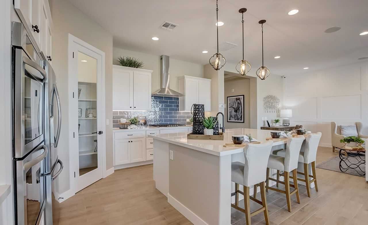 Elegant Modern Kitchen with Island in Mirada Crossing Community Modern kitchen with white cabinets, island, pendant lights, and stainless steel appliances in Mirada Crossing.