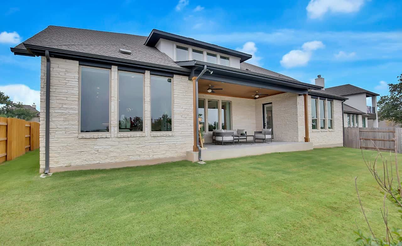 Modern Stone Home in Oaks at San Gabriel, Texas Modern stone home with large windows, covered patio, lush lawn in Oaks at San Gabriel, Texas.